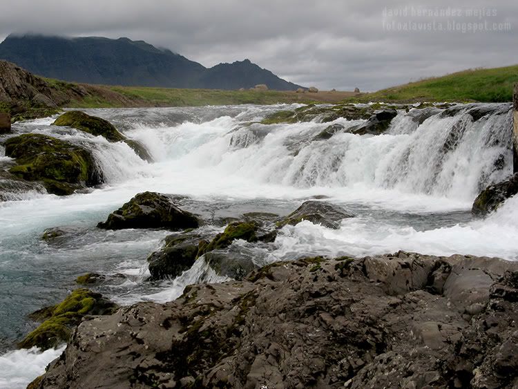 Una pequeña cascada o unos rápidos en un frío río de Islandia con un cielo tenebrista Rápidos islandeses