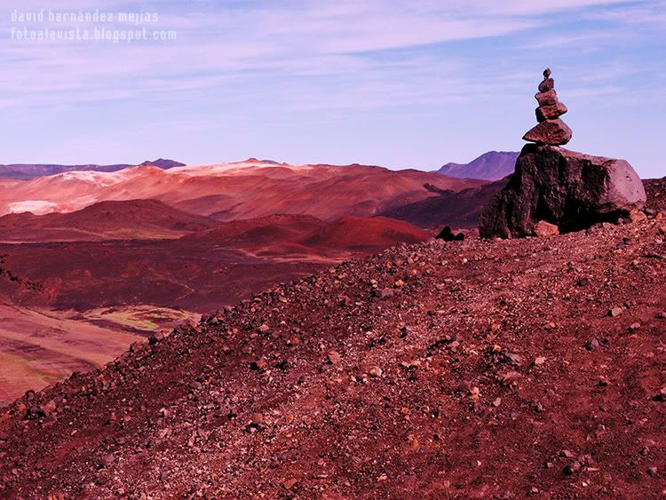 Piedras colocadas en equilibrio por los viajeros sobre la cima exterior del volcán Hverfell, en Islandia, con montañas al fondo Equilibrios naturales
